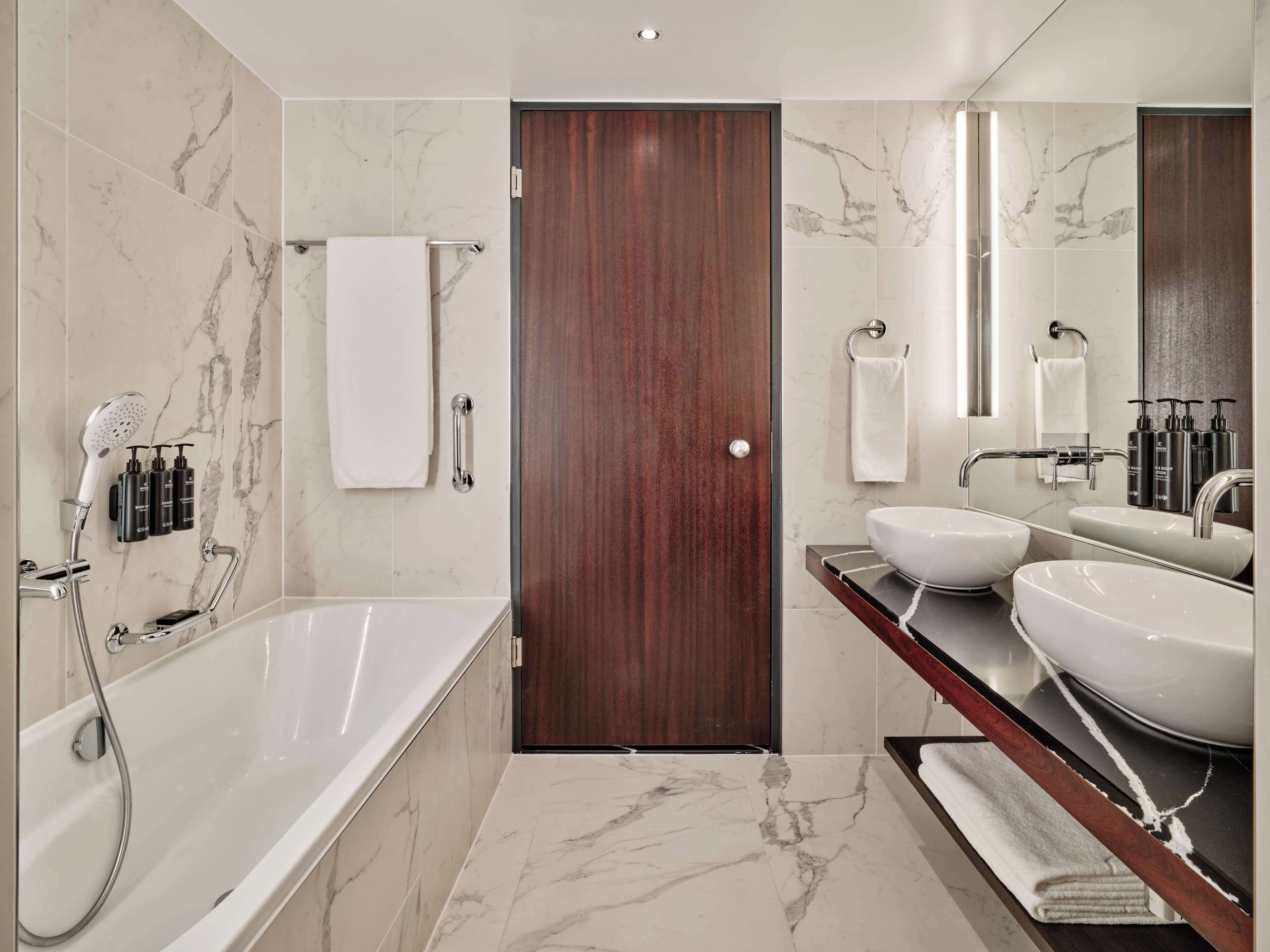 Ein modernes Badezimmer mit Badewanne, zwei Waschbecken und einem großen Spiegel.