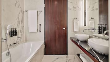 A modern bathroom with a bathtub, two sinks, and a large mirror.