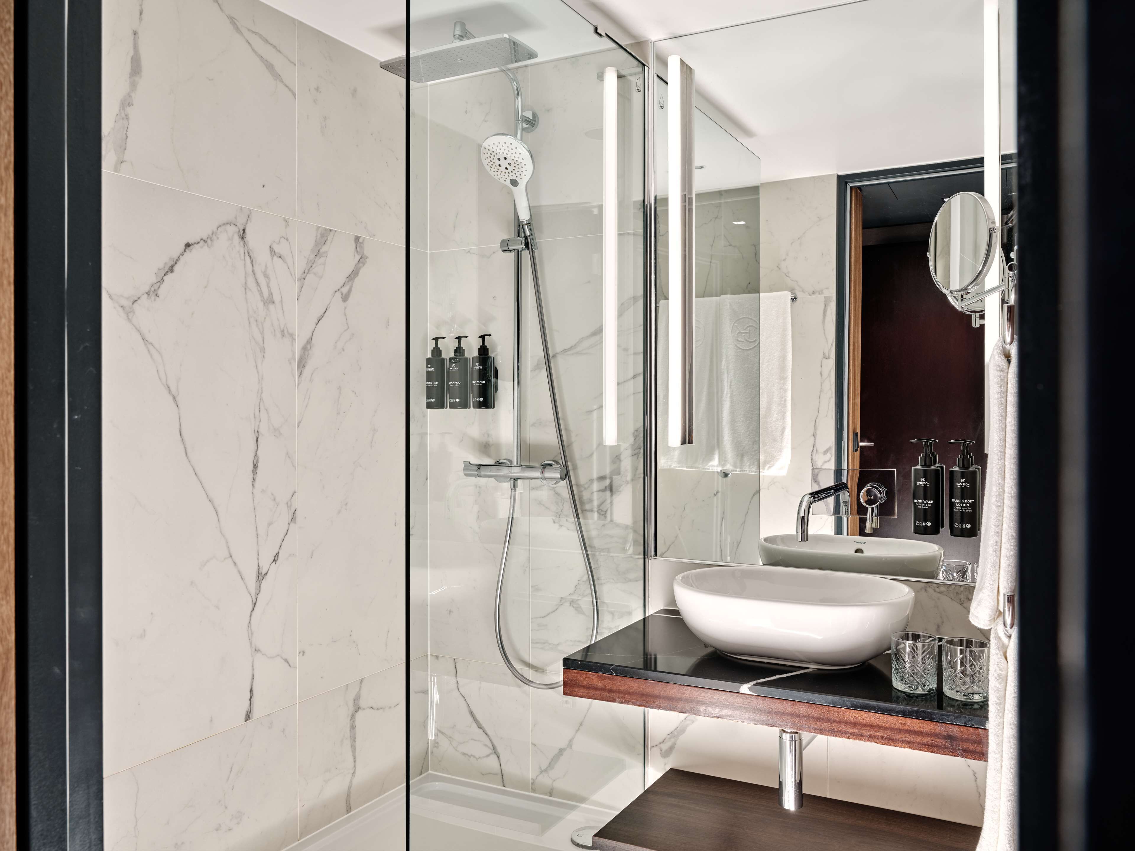 Une salle de bain moderne avec une douche à parois de verre, un lavabo blanc et un miroir.