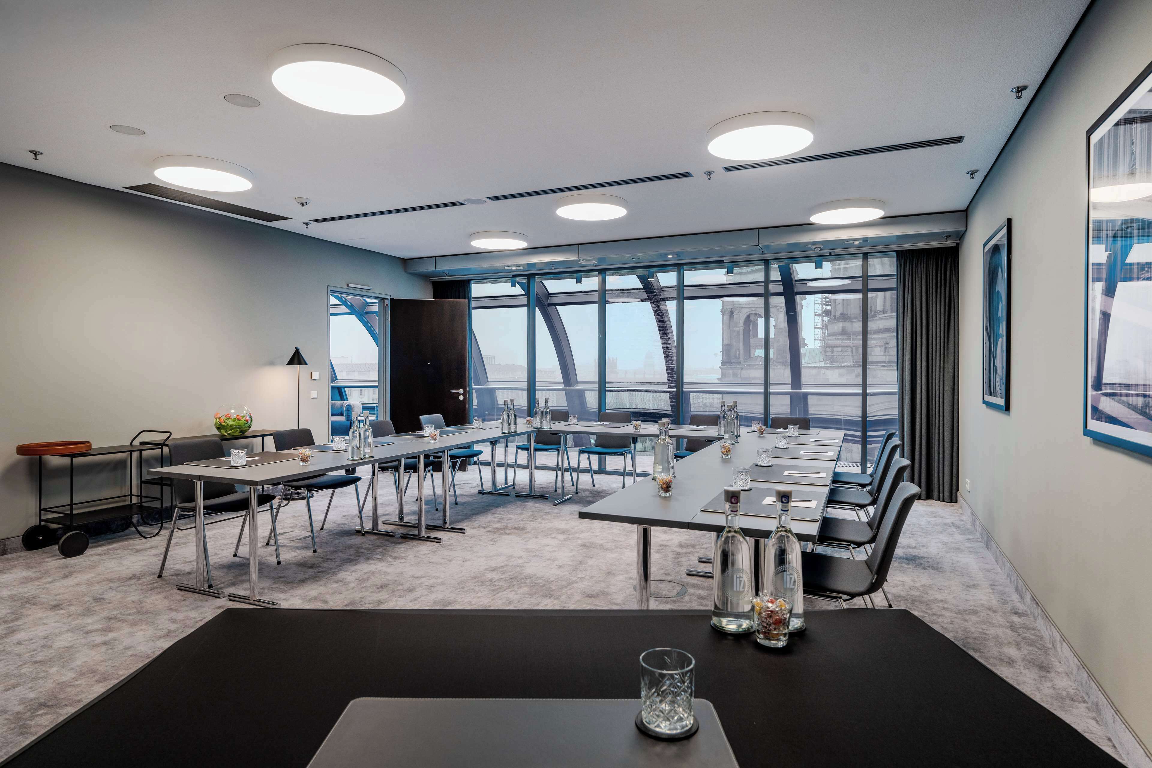 A modern conference room with a large table, chairs, and a view of a bridge through large windows.