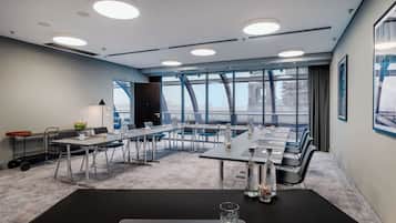 A modern conference room with a large table, chairs, and a view of a bridge through large windows.