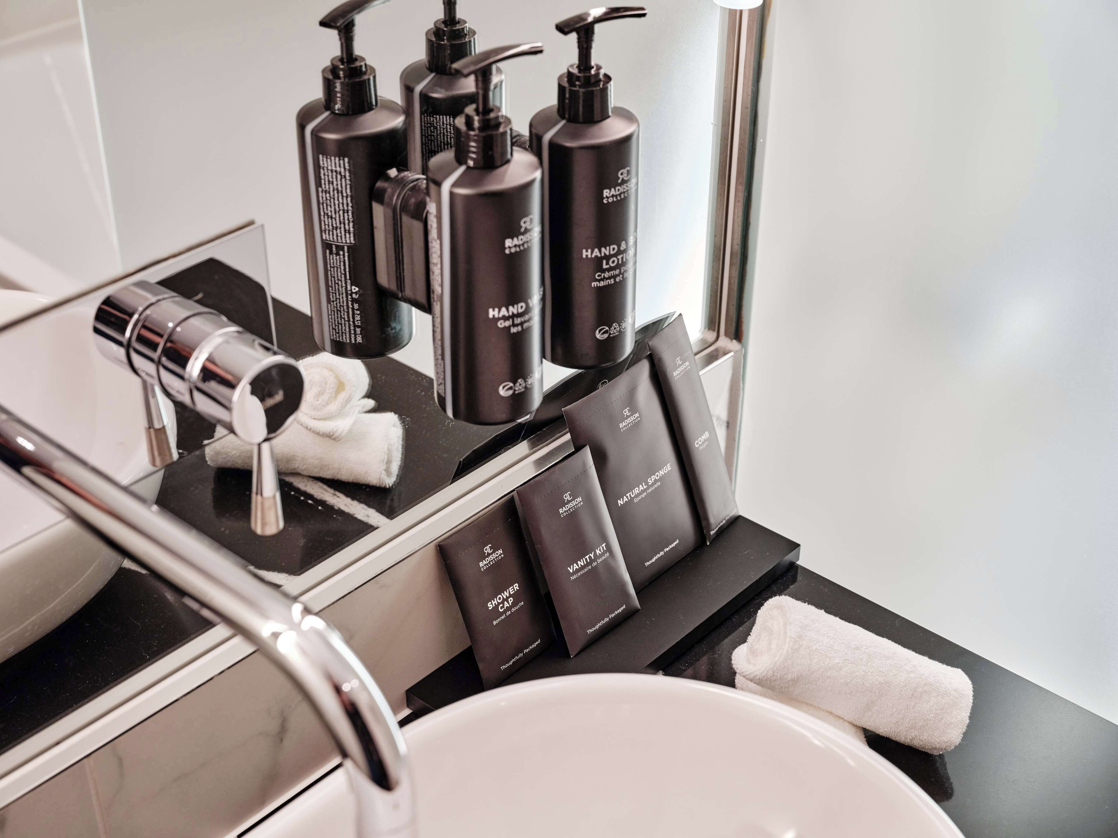 A bathroom vanity with black toiletries, a towel, and a shower cap.