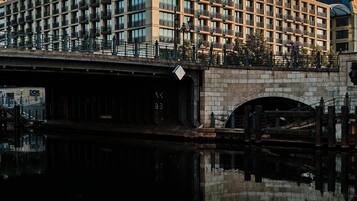 Un hotel moderno con fachada de vidrio y balcones, reflejado en el agua.