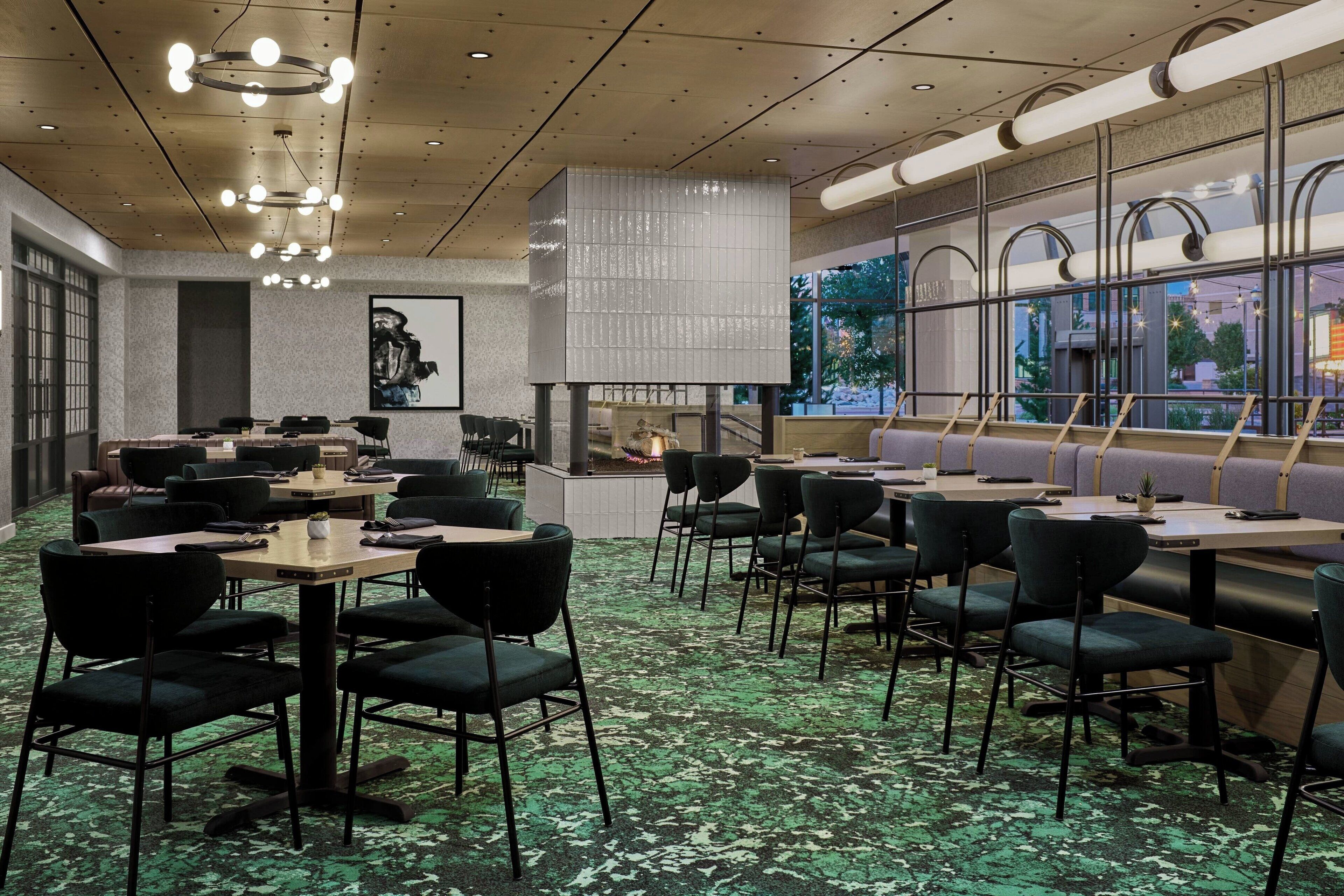 Um restaurante moderno com várias áreas de refeição, incluindo um bar e um espaço com vista para o exterior.