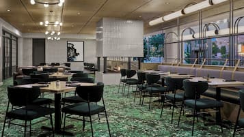 A modern restaurant with multiple dining areas, including a bar and a seating area with a view of the outdoors.