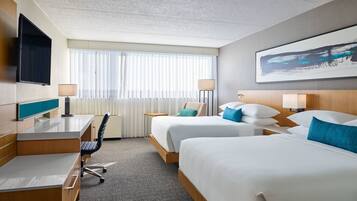 A hotel room with two beds, a desk, a chair, a TV, and a window with curtains.