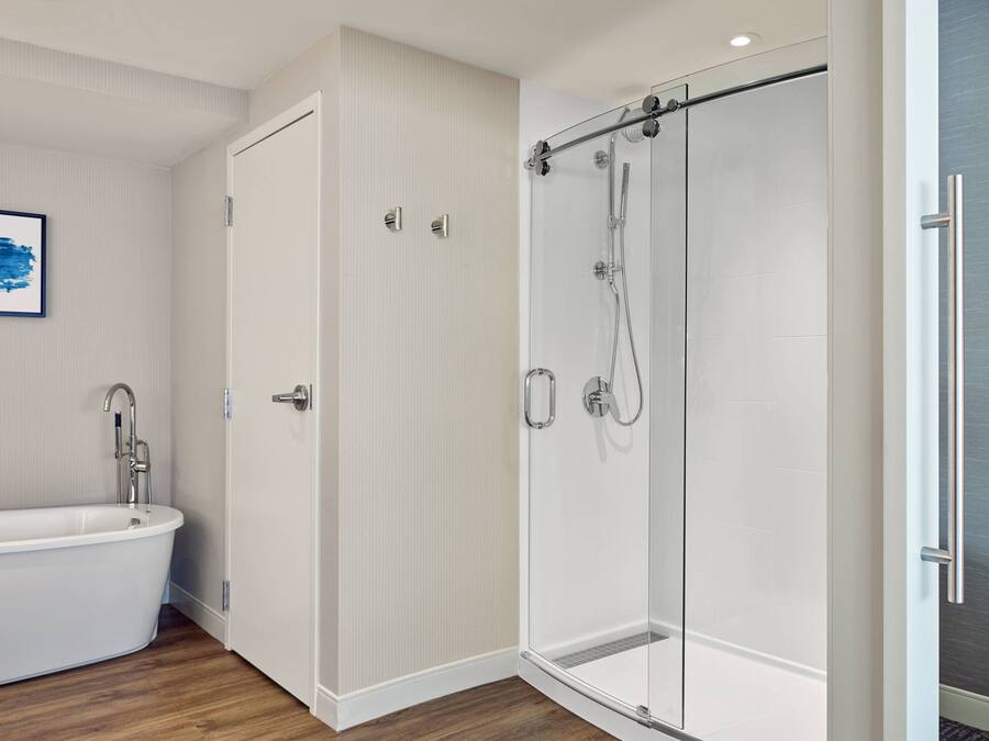 Uma casa de banho moderna com uma banheira independente, um chuveiro com proteção de vidro e uma porta que dá para outro espaço.