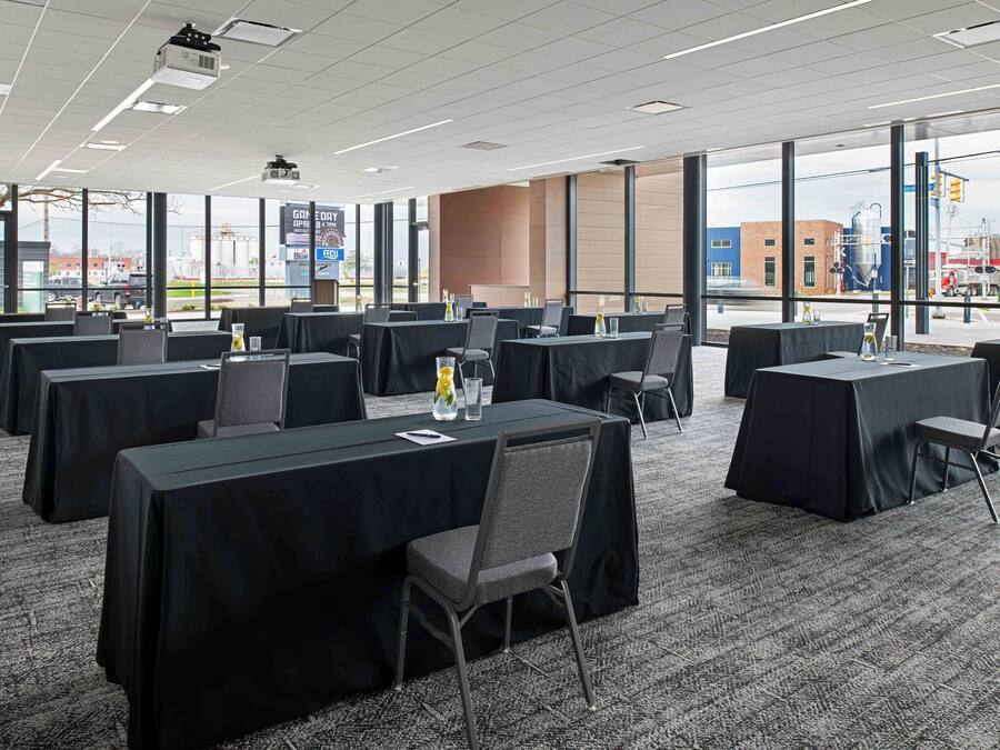 A conference room with multiple tables, chairs, and a projector.