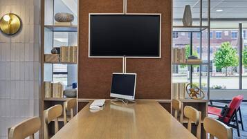A conference room with a large table, chairs, a computer, and bookshelves with various items.