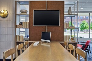 A conference room with a large table, chairs, a computer, and bookshelves with various items.