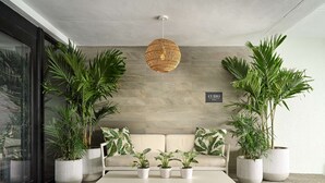 Un salon moderne avec un canapé blanc, une table basse et de grandes plantes en pot.