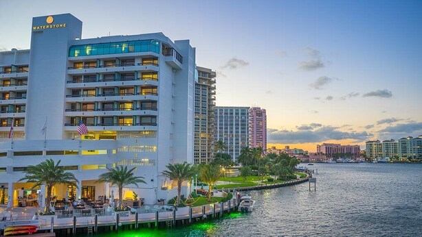 Un hôtel situé au bord de l’eau, avec plusieurs étages, un quai et une marina.