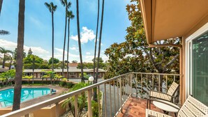 A balcony with a pool, palm trees, and outdoor seating. - Best Western Pine Tree Motel (Chino)