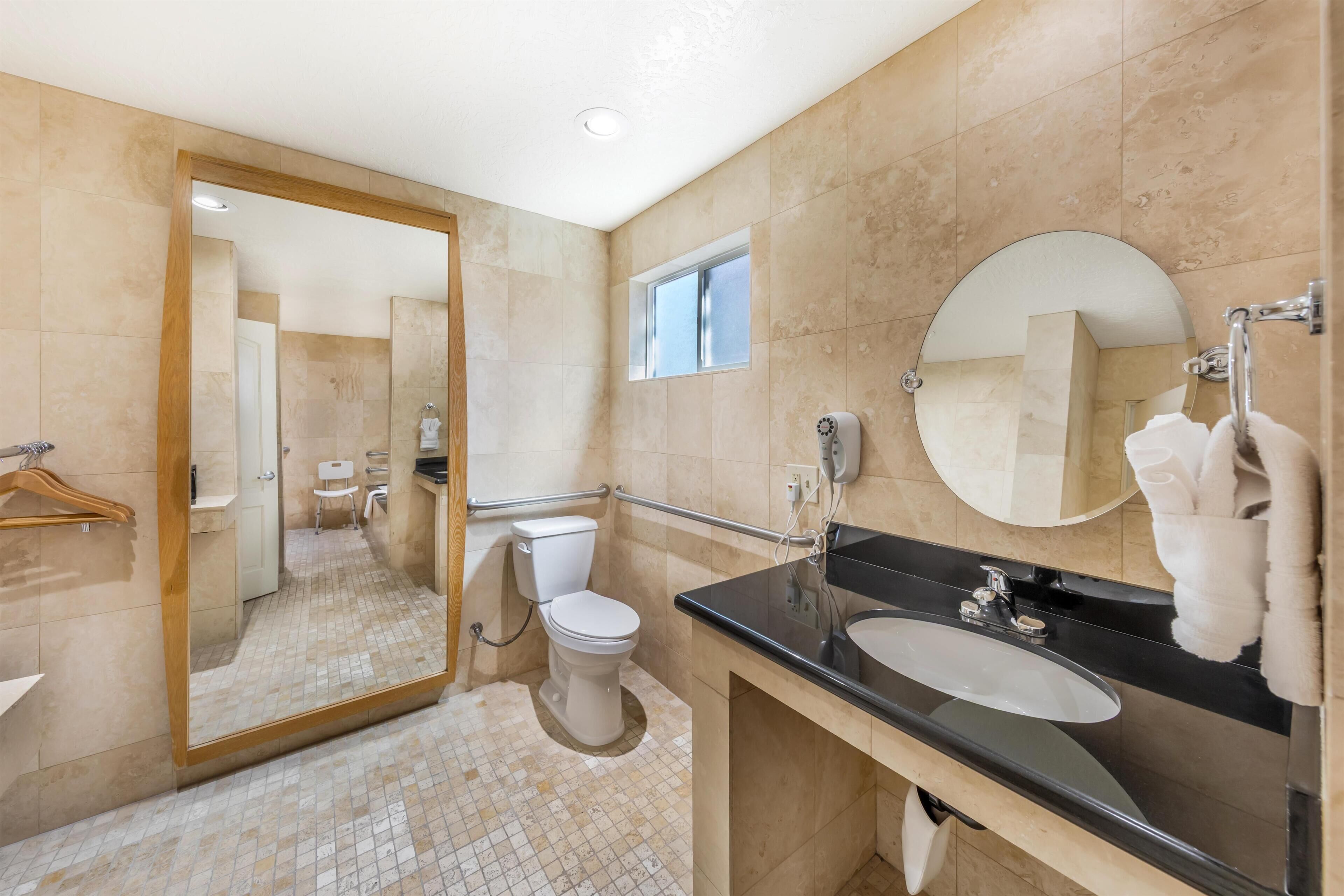 Un baño moderno con inodoro, lavabo, espejo y ventana.