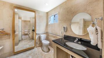 Un baño moderno con inodoro, lavabo, espejo y ventana.