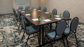 A conference room with a long table, chairs, and a projector screen.
