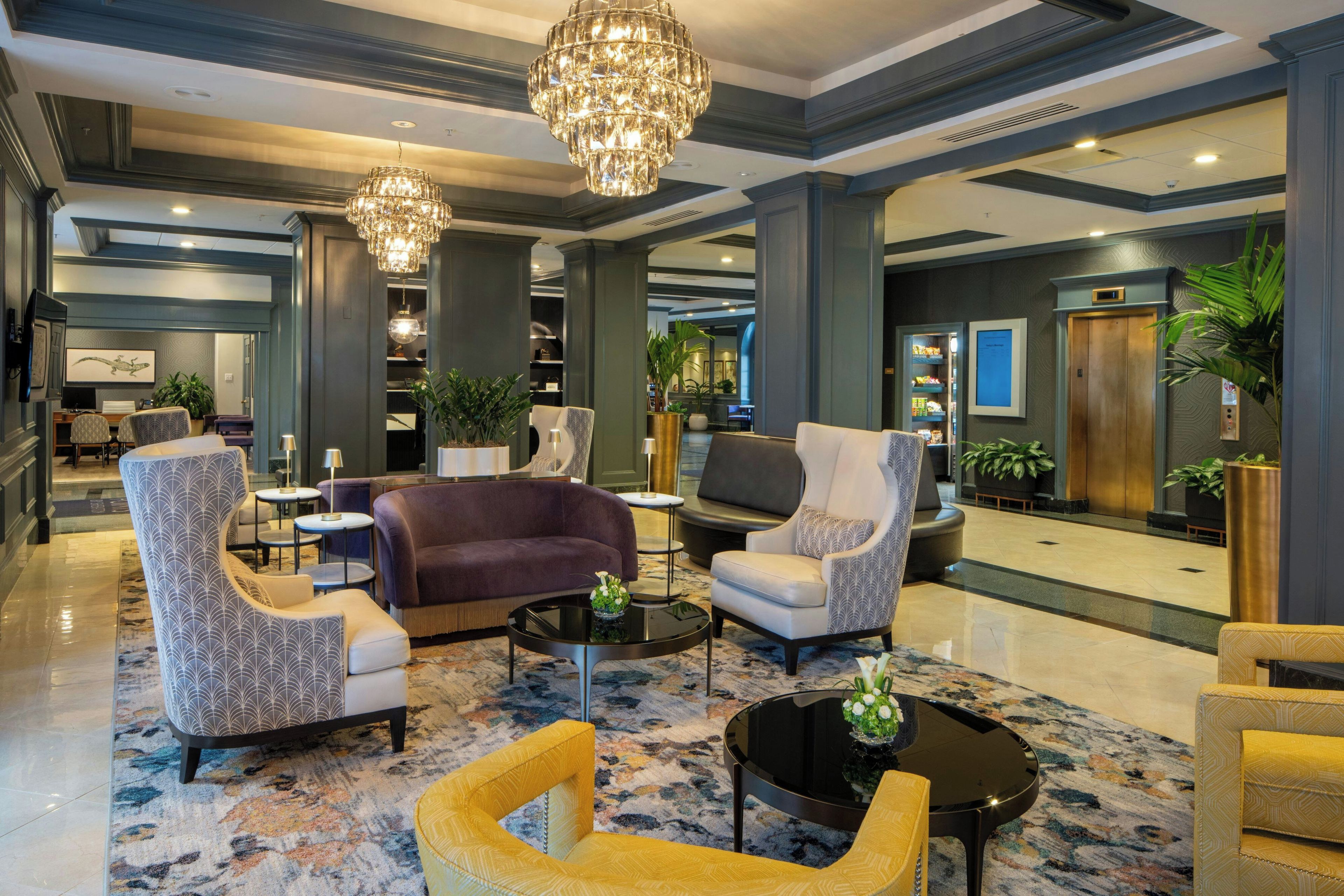 Un hall d’entrée spacieux, doté de meubles modernes, d’un lustre et d’un comptoir de réception.