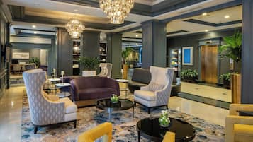 A spacious lobby with modern furniture, a chandelier, and a reception desk.