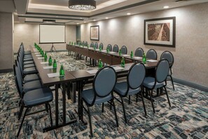 A conference room with a long table, chairs, a projector screen, and a carpeted floor. - Four Points By Sheraton French Quarter (New Orleans)