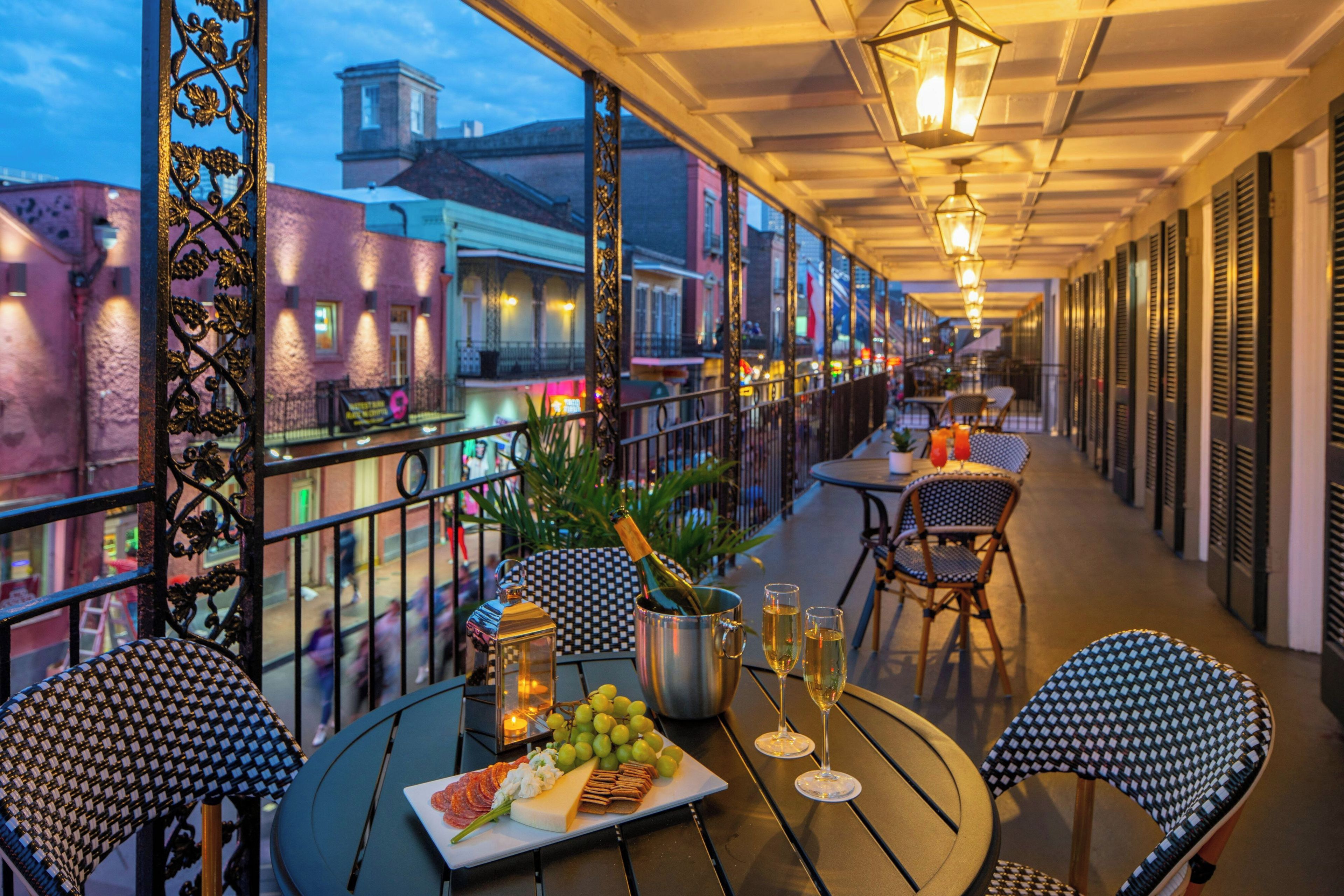 Una terraza exterior con mesas y sillas, una botella de champán y un plato de comida.
