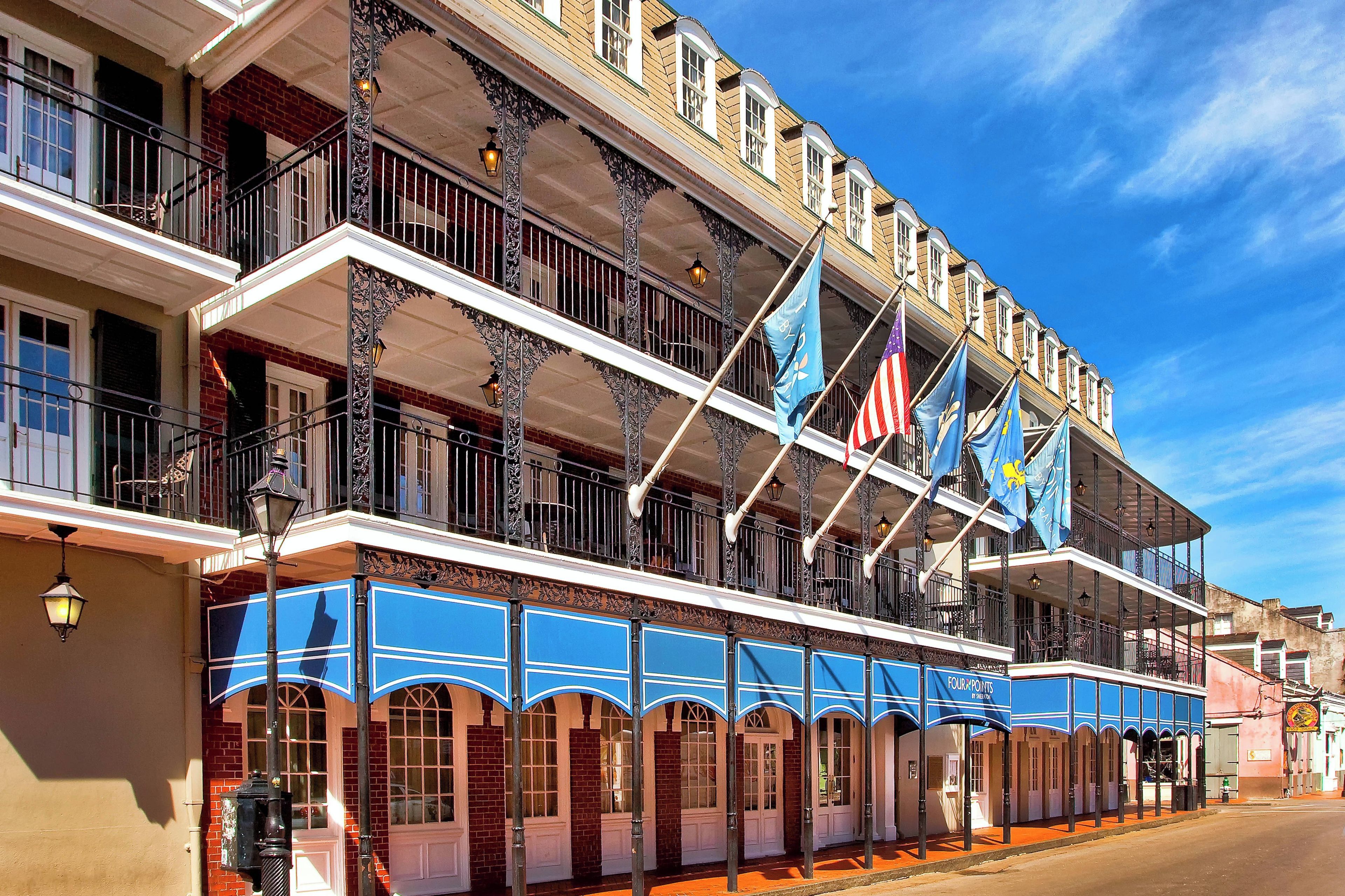 A multi-story building with balconies, a covered walkway, and flags.