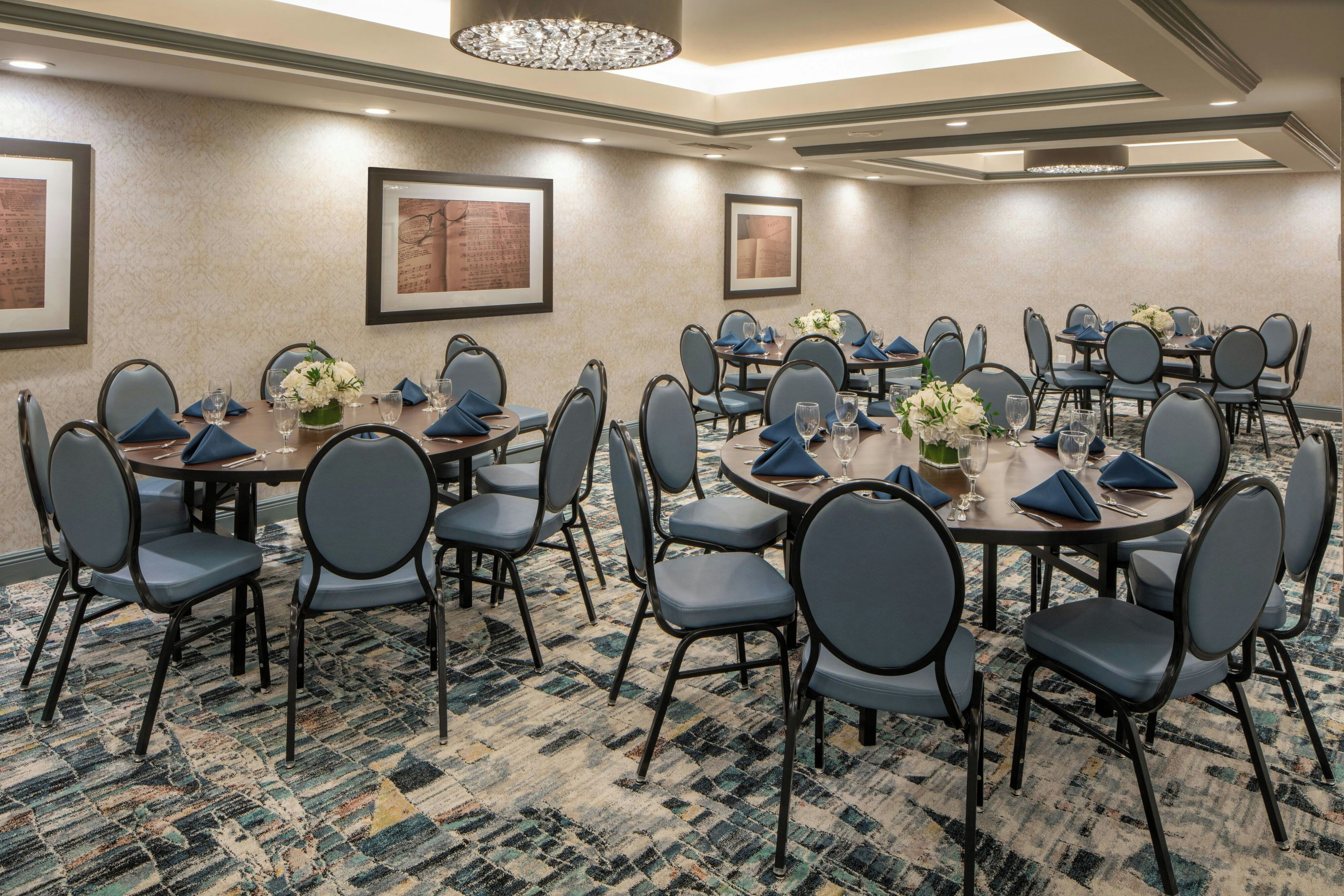 A conference room with round tables, chairs, and framed artwork on the walls.