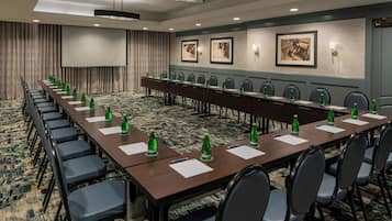 A conference room with a long table, chairs, and a projector screen.