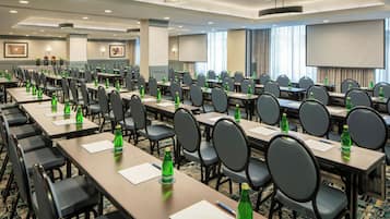 A conference room with multiple tables, chairs, and presentation screens.