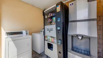 A laundry room with a washing machine, dryer, and a vending machine.