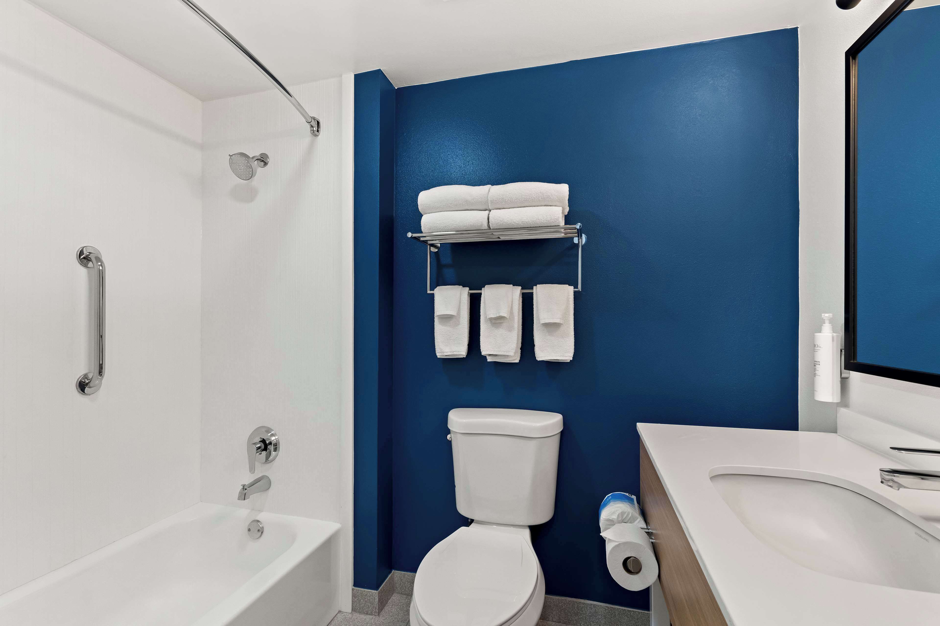 A modern bathroom with a white bathtub, a toilet, and a sink.