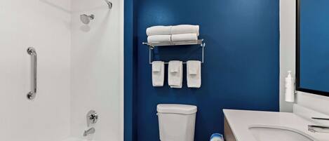 A modern bathroom with a white bathtub, a toilet, and a sink.