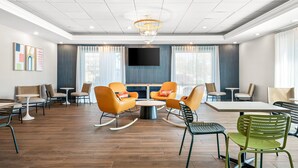 A modern hotel lobby with a central seating area, a flat-screen TV, and large windows. - Spark by Hilton Hummelstown Hershey (Hummelstown)