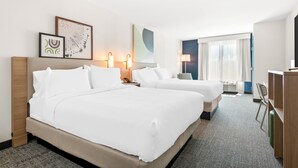 A hotel room with two beds, a desk, a chair, and artwork on the walls. - Spark by Hilton Hummelstown Hershey (Hummelstown)