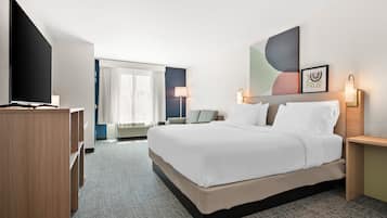 Habitación de hotel con una cama grande, televisor de pantalla plana, escritorio y ventana con cortinas.