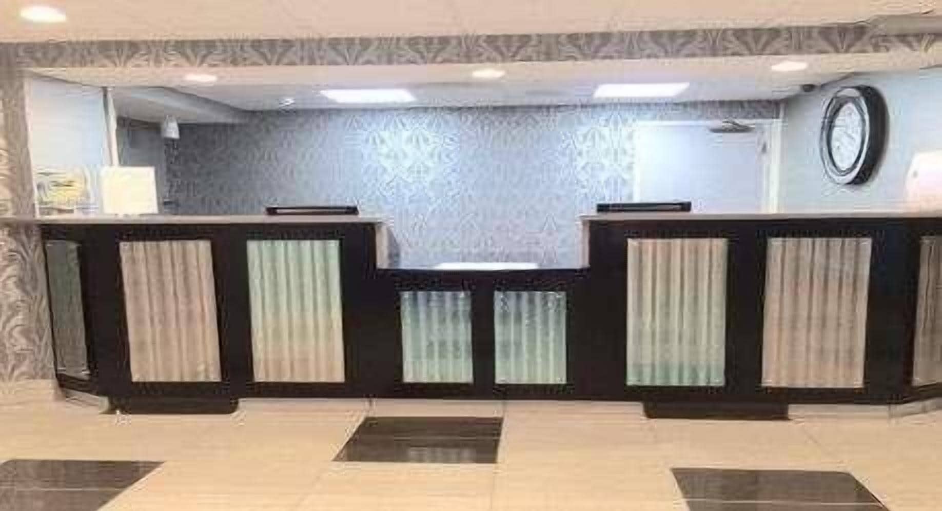 Una zona de recepción con mostrador, pared estampada y un reloj.