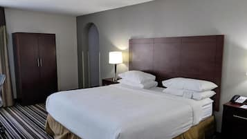 A hotel room with a large bed, a wardrobe, a bedside table with a lamp, and a telephone.