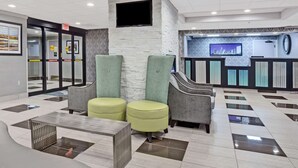 Un vestíbulo con mostrador de recepción, zona de estar y escalera.