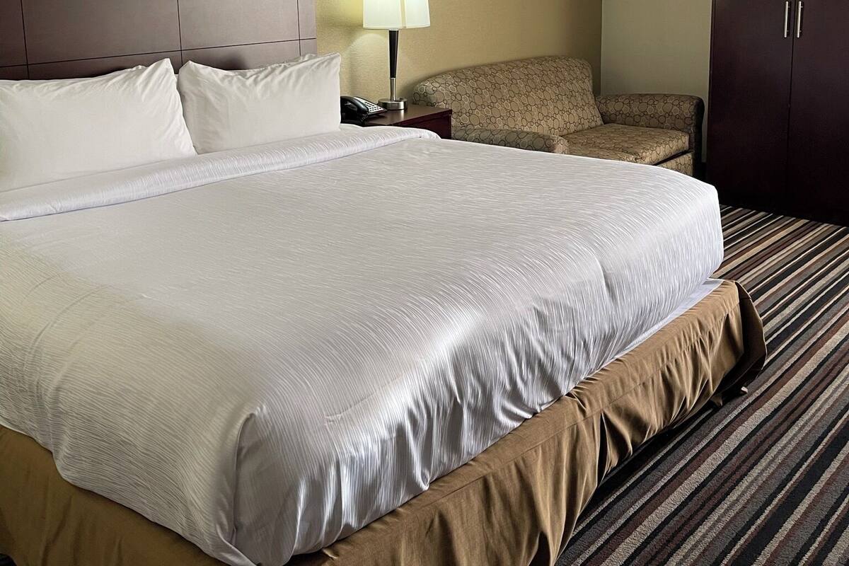 Une chambre d’hôtel avec un grand lit, un bureau avec une lampe, une chaise et une armoire.