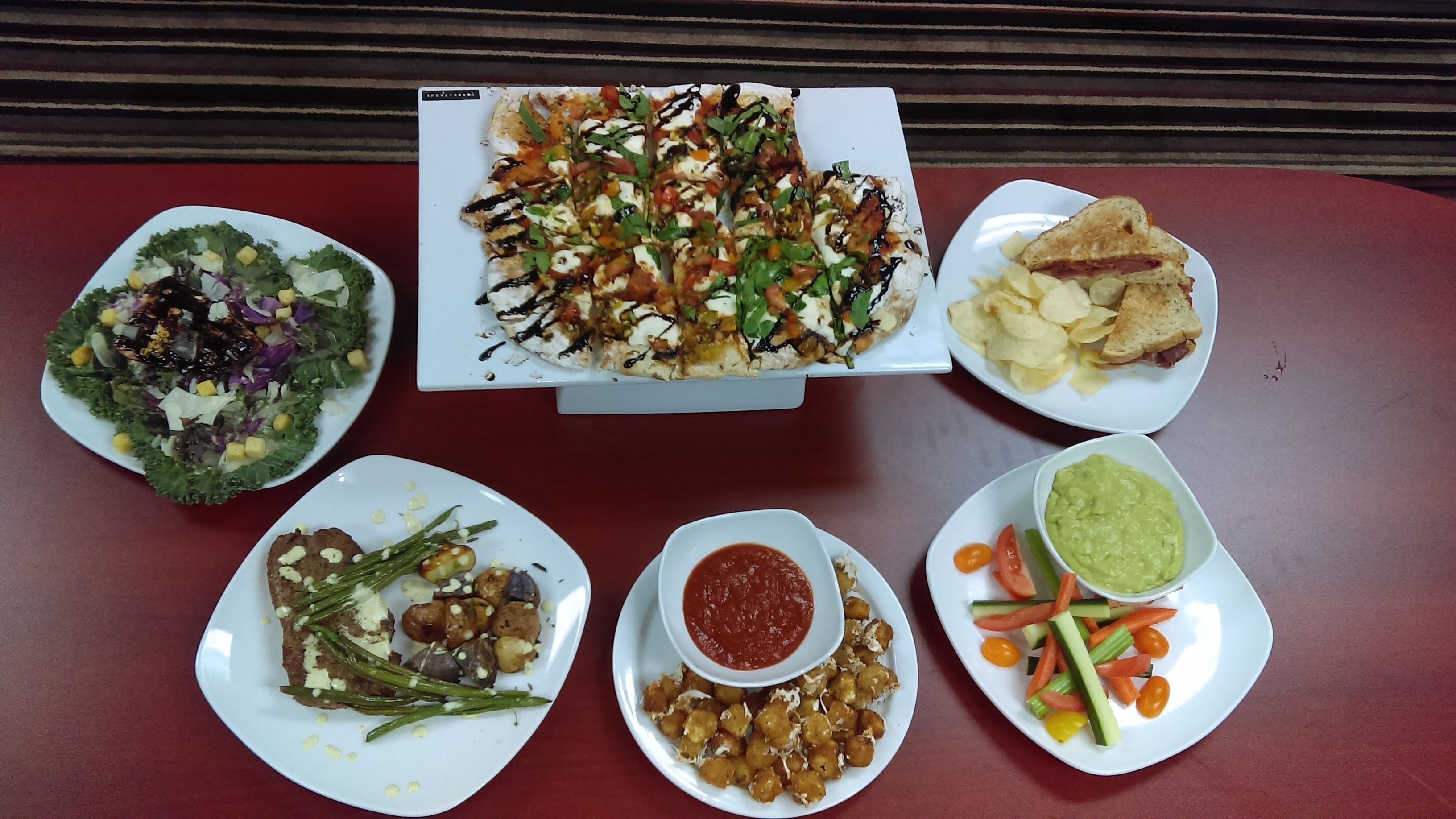 A table with various dishes including pizza, salad, chips, and vegetables.