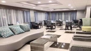 Un área de estar moderna con sofás, sillas y una pequeña mesa.
