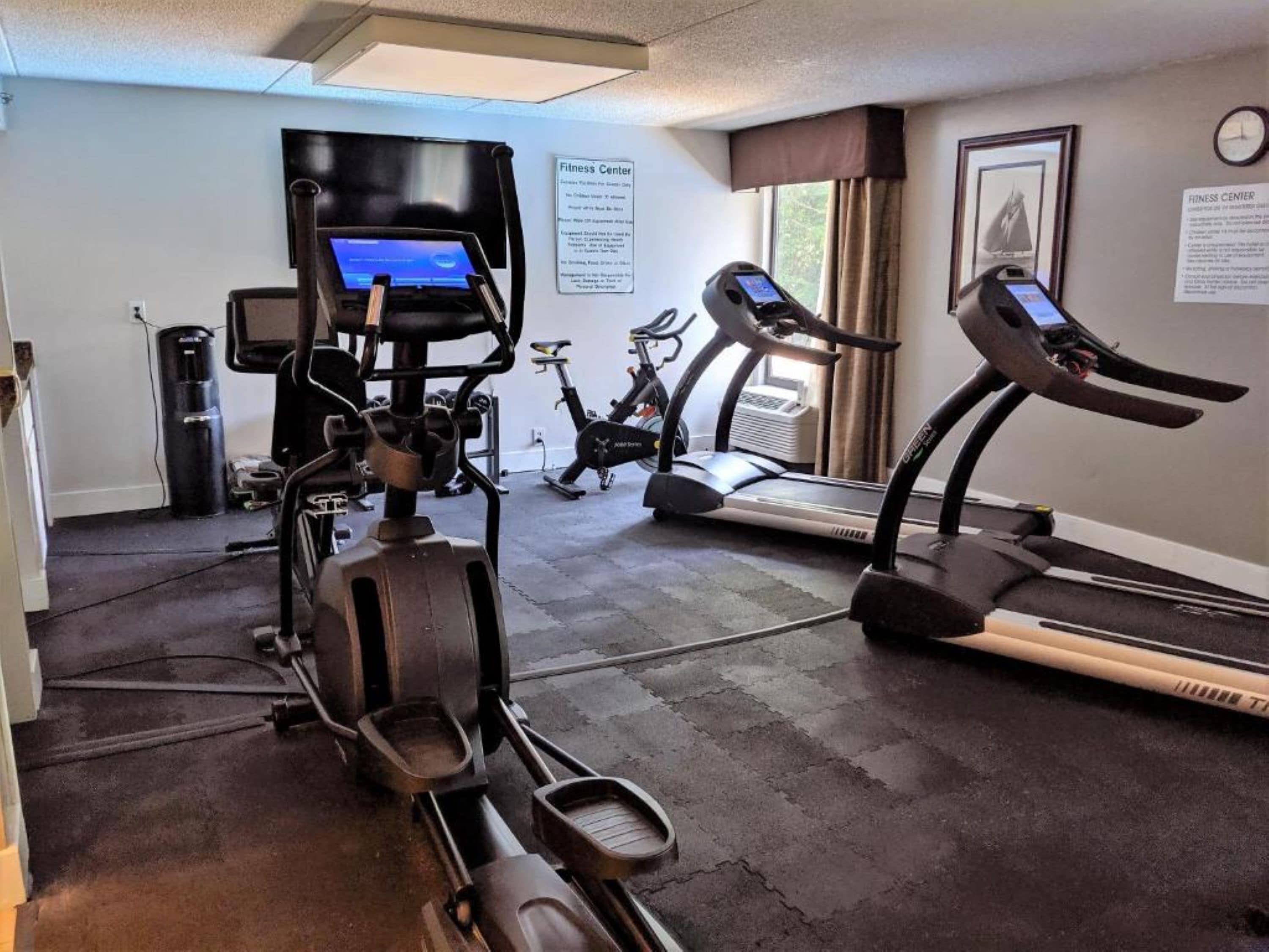 Un gimnasio con máquinas de cardio, cinta de correr y bicicleta estática.