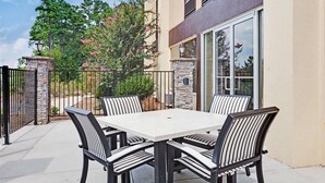 Un patio con una mesa y sillas, un muro de piedra y un árbol con flores rosadas.