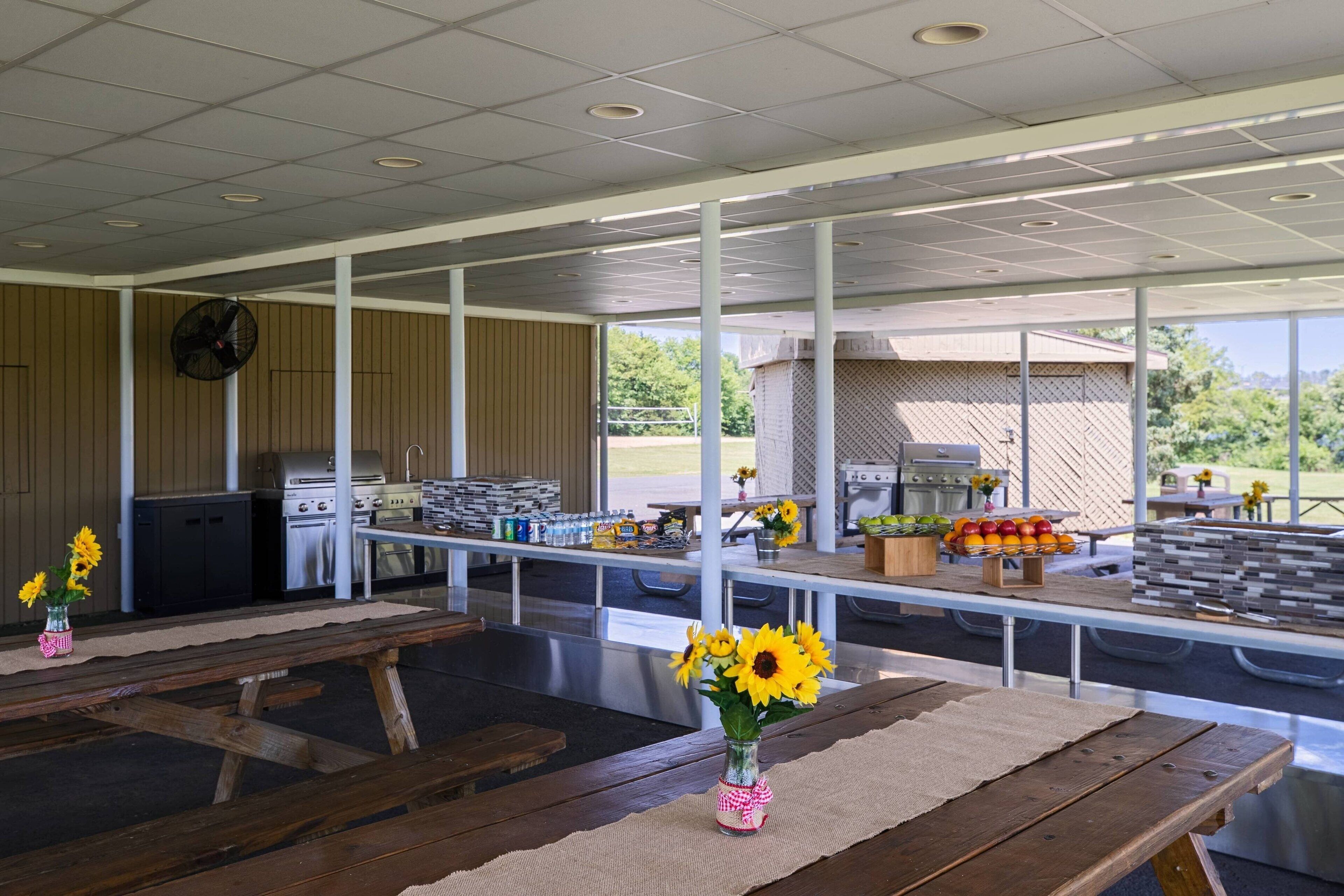 Un espace extérieur aménagé avec des tables de pique-nique, un barbecue et un coin barbecue.