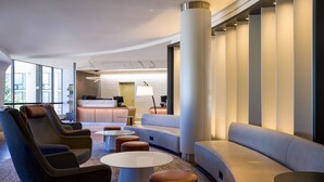 A modern lobby with seating areas, a reception desk, and large windows. - Washington Dulles Airport Marriott (Sterling)