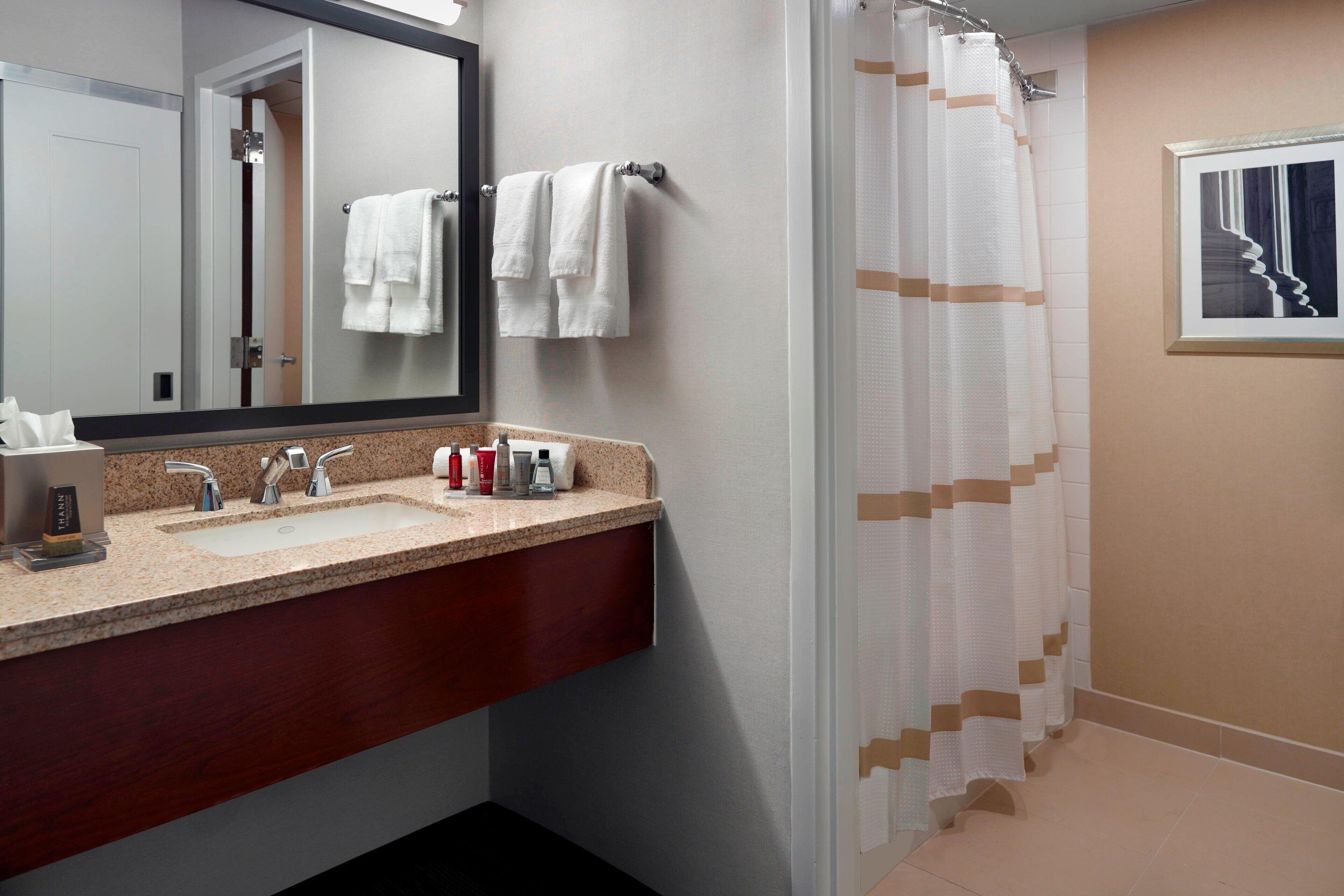 A bathroom with a sink, mirror, and shower curtain.