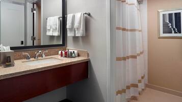 A bathroom with a sink, mirror, and shower curtain.