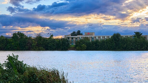 A hotel with a view of a lake and a cloudy sky. - Washington Dulles Airport Marriott (Sterling)