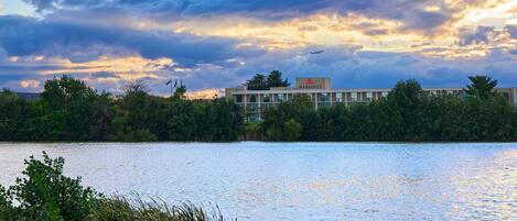 A hotel with a view of a lake and a cloudy sky.
