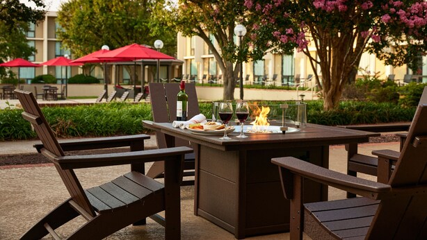 An outdoor dining area with a table, chairs, and a fire feature. - Washington Dulles Airport Marriott (Sterling)