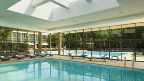 A swimming pool with lounge chairs and a glass ceiling. - Washington Dulles Airport Marriott (Sterling)